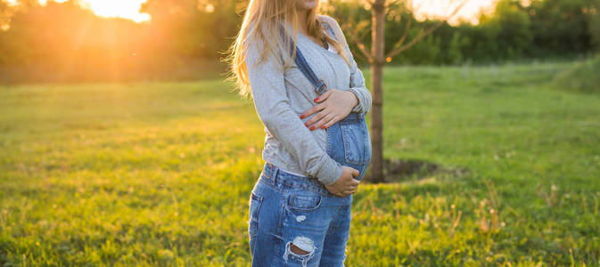 孕妇在户外拥抱她的肚子