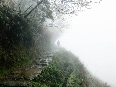 男子在潮湿的路径在山坡上的雨