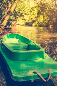 塑料的绿色船和平静河与竹树上自然背景