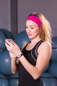 年轻女子健身跟踪与智能手机在健身房