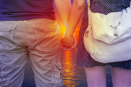 年轻夫妇牵手在海滩上日落