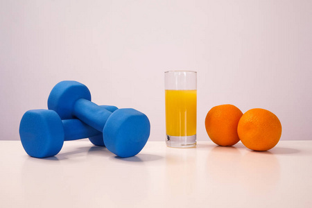 健康饮食的概念。小哑铃。苹果汁。跳绳。测量带腰。在白色背景上的橘子。健康的生活方式。体育