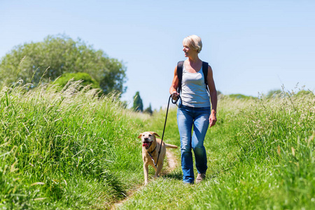 成熟的女人，带着狗在风景徒步旅行