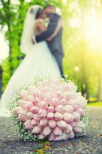 婚礼花束。在公园里和背景下的一对年轻夫妇在浪漫地拥抱著地上躺着的婚礼花束