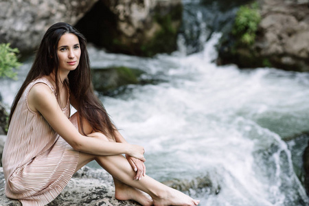 美丽的黑发，坐在一块岩石在河 水 瀑布。美丽的大自然，自然的光线，柔软，填充