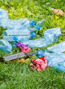 乱草堆在公园,乱抛垃圾的环境概念的绿色草地上的垃圾照片