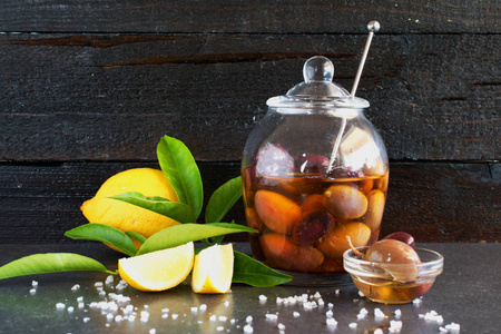 用橄榄木背景加柠檬，橄榄油中的玻璃碗海盐。希腊的传统食物