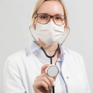 年轻的女医生用听诊器和医疗面罩