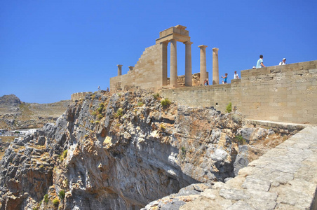 在岩石上的著名的仿古希腊神庙废墟上观希腊岛屿科斯市的罗德和步行游客。著名的观光场所