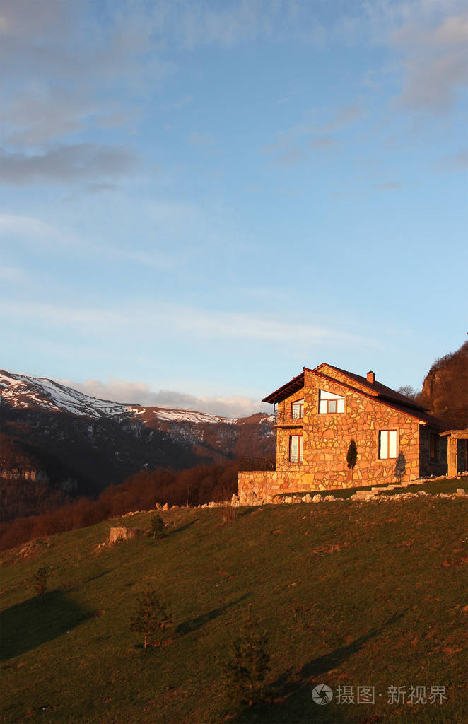 背景下的雪山日出垂直山上孤独石头房子
