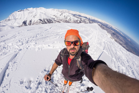 成人 alpin 滑雪与胡子 太阳镜和帽子，在湛蓝的天空与美丽的意大利阿尔卑斯山的雪坡上采取自拍照。健美的形象 复古风格 