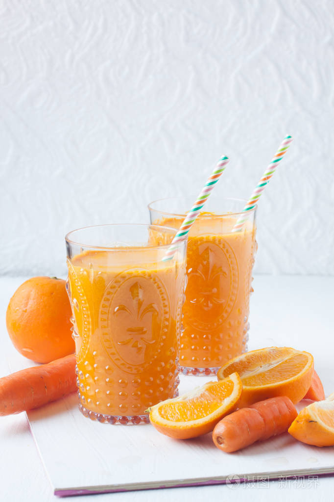 在白色背景上的橙色和胡萝卜汁
