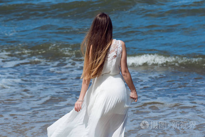 年轻迷人的黑发女子在海岸上白色夏天穿裙子的漂亮女孩