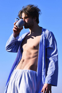 蓝色条纹的睡衣饮料从杯中的白种人男子气概