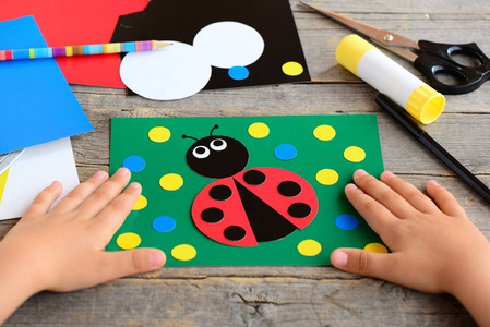 孩子作瓢虫从彩色的纸。夏卡着一张小木桌上文具纸瓢虫。简单的纸圈工艺品为教孩子们削减和胶水。发展孩子的运动技能
