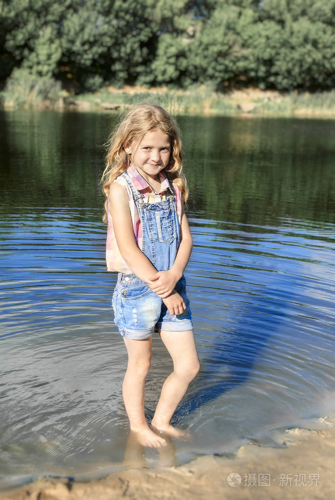 可爱女孩站在赤脚在河里阳光明媚的夏日