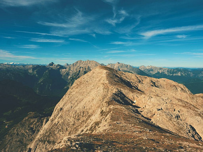 查看在高山悬崖和山谷。太阳在地平线上，蓝色天空与少云。阿尔卑斯山