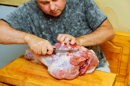 男人在家庭厨房的木制砧板上切肉