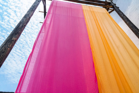 悬挂晾干后传统染色工艺的彩色织物照片