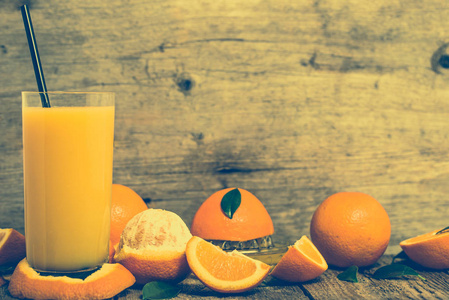 榨的橙汁和新鲜的橘子水果仿古木制的桌子上