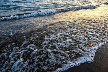 在日落期间接近沙滩的海浪