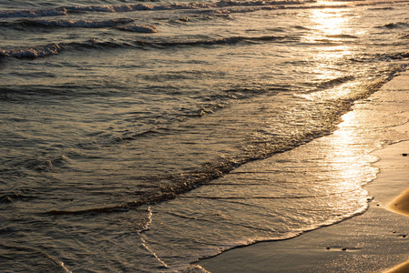 在日落期间接近沙滩的海浪