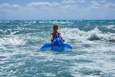骑海豚一个骑充气海豚的女孩在海浪中游泳.