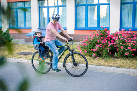 骑自行车，父亲与快乐的孩子骑自行车在户外的家庭