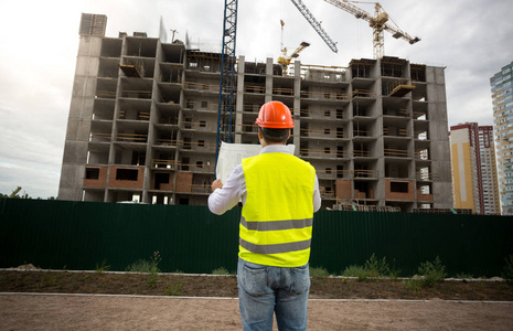 阅读蓝图建筑工地上的年轻建筑工程师