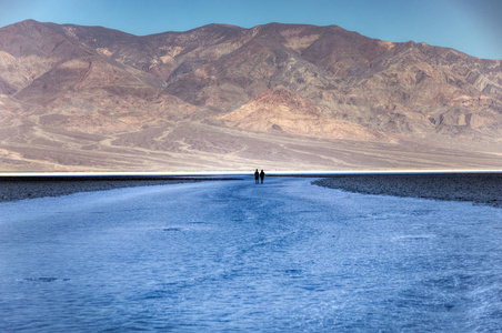 2 名男子在恶水盆地的盐滩上行走