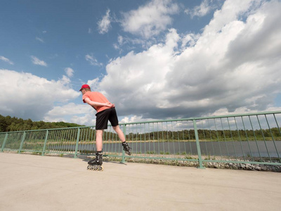 滚轴溜冰在行动中。男人骑在内联溜冰鞋骑沿长廊扶手，在背景中的天空