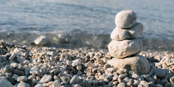 堆鹅卵石石头在蓝色的大海，在背景中