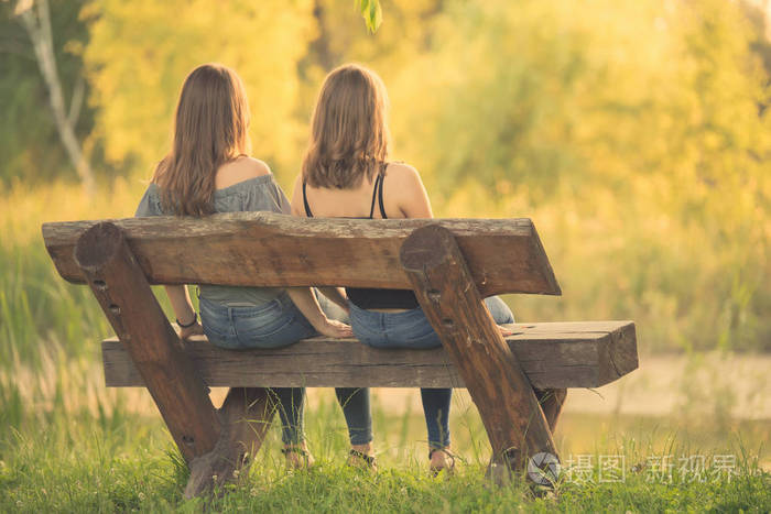 两个美丽的女人坐在长椅上和放松