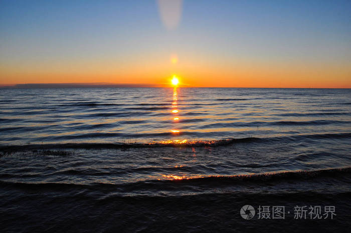 在拉多加湖的黎明.太阳升起上面反映在海浪中的湖