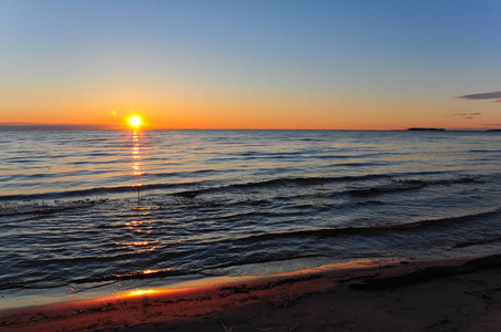 在拉多加湖的黎明。太阳升起上面反映在海浪中的湖