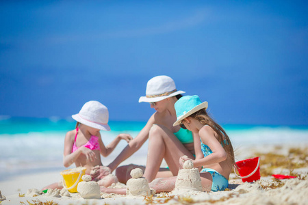 家庭的母亲和孩子做沙子城堡在热带海滩