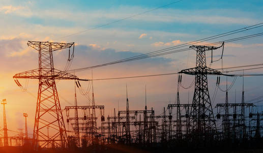 日落时稻田的电力输电线路照片