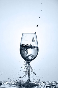 喝纯净水倒入一透明酒杯站在玻璃与液滴光背景上