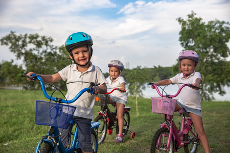 三个孩子骑一辆自行车。孩子们在公园里骑自行车头盔。美丽的孩子。关闭