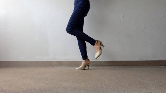 在高的女人腿跟金色凉鞋站在地上,室外背景照片