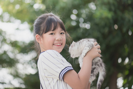 美丽的亚洲女孩抱着可爱的小猫在公园里阳光明媚