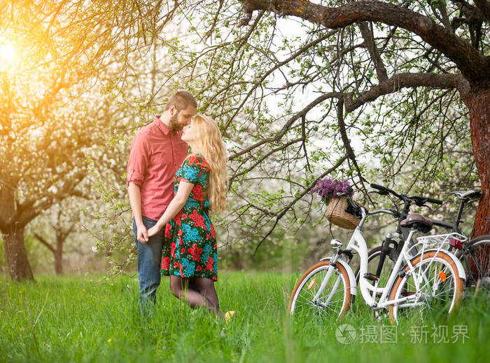 恩爱的小夫妻与自行车在春天的花园