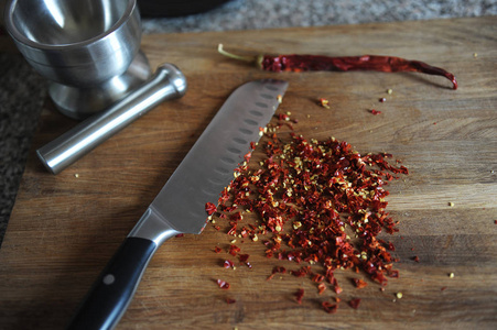 切碎干的辣椒在木板上.刀和砂浆的组成照片