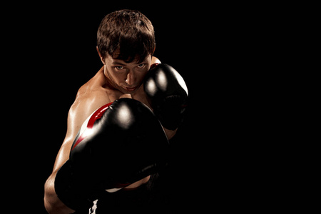 男性的拳击手拳击沙袋在与戏剧性的前卫照明，在一个黑暗的工作室