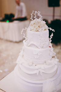 美丽的白色和彩色的婚礼蛋糕。新娘和新郎削减他们的婚礼蛋糕