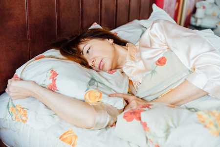 肖像的迷人的中间岁女人睡在床上，在阳光明媚的早晨的红头发
