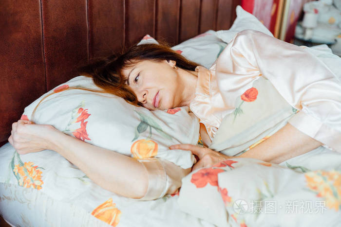 肖像的迷人的中间岁女人睡在床上在阳光明媚的早晨的红头发