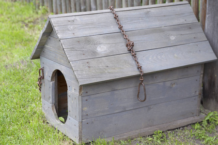 栅栏屋顶生产一个有铁链的木制狗窝和栅栏附近的破屋顶照片