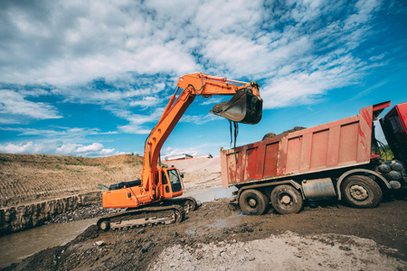工作挖掘机在施工现场，在土方工程自卸车装车