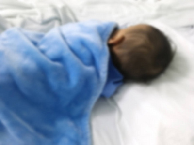 模糊的病症亚洲孩子用蓝色布睡觉在病床上